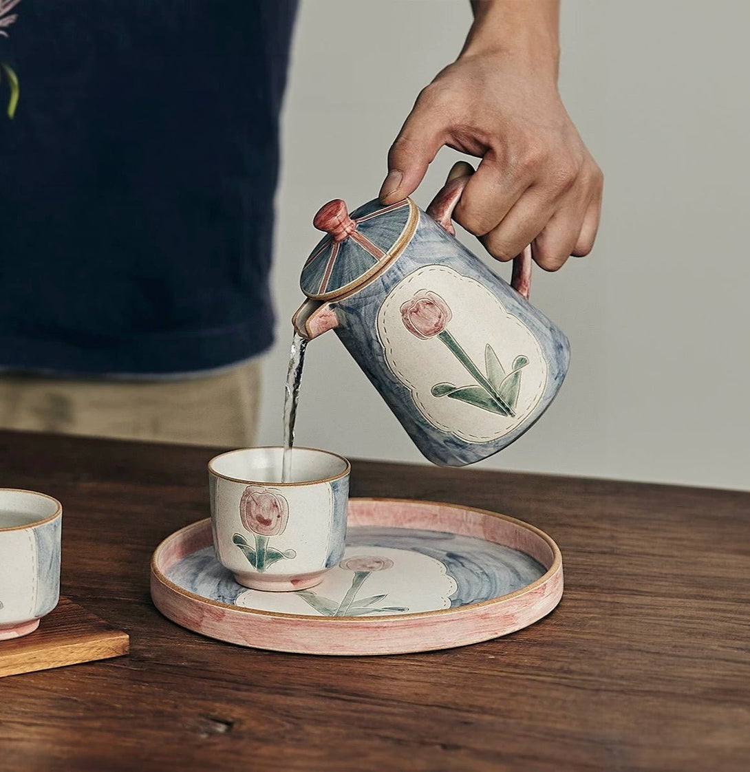 a set of teapot, cup and saucer in floral patterns, primarily in blue and pink colors.
