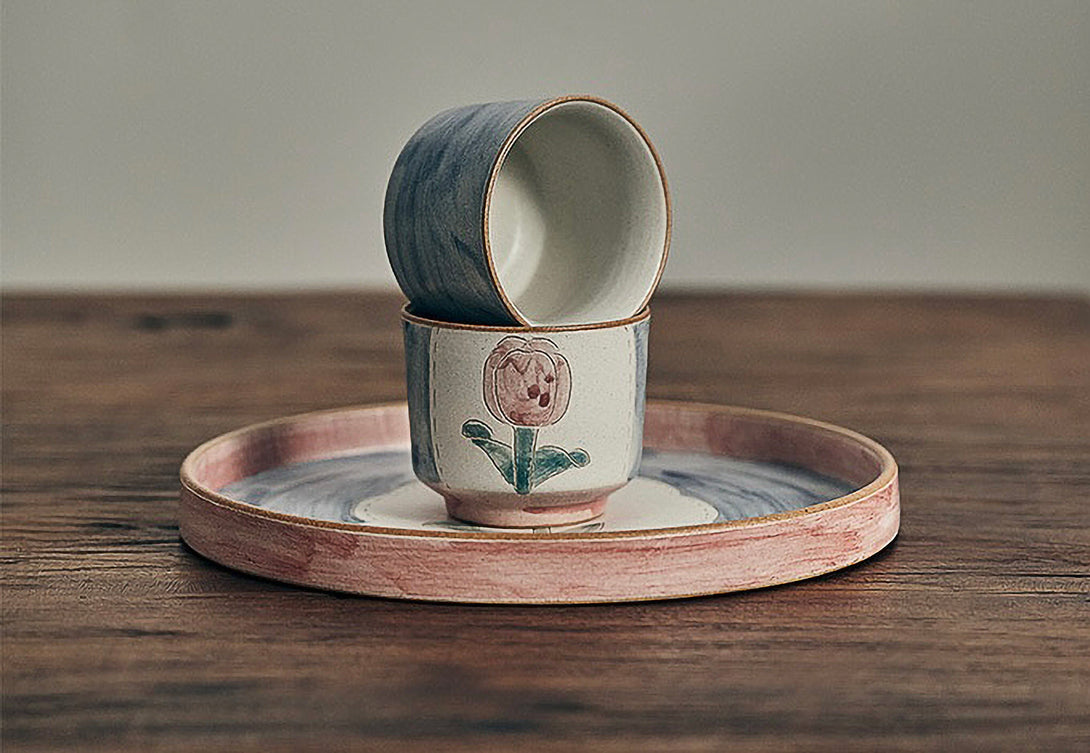 ceramic cups and tray in floral patterns, primarily in blue and pink colors.