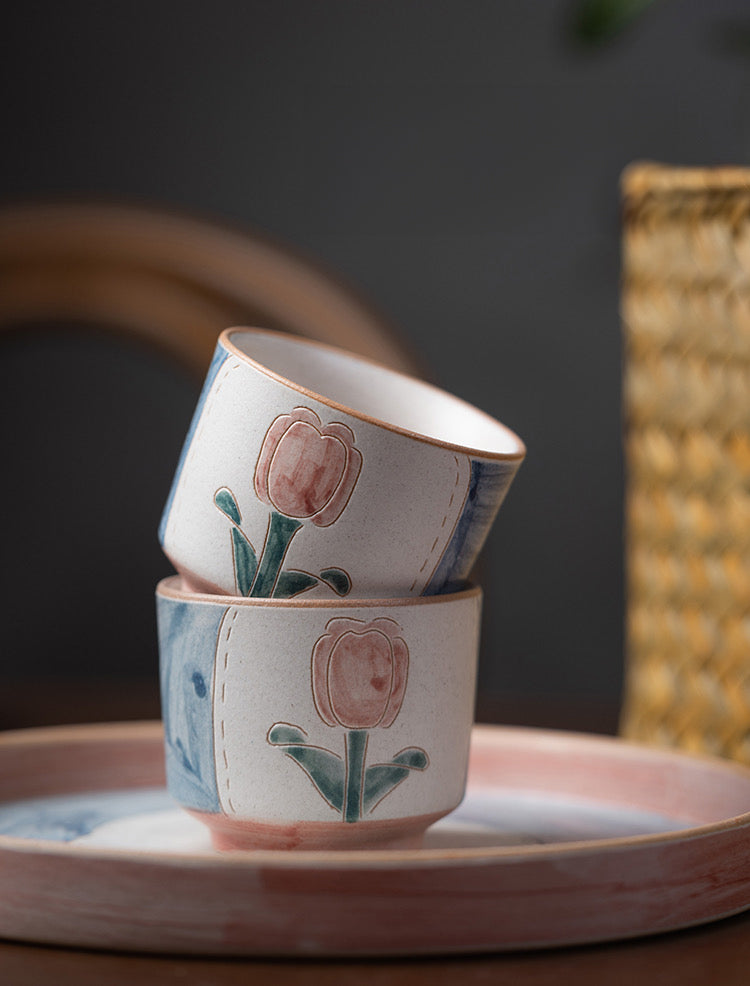 ceramic cups and tray in floral patterns, primarily in blue and pink colors.