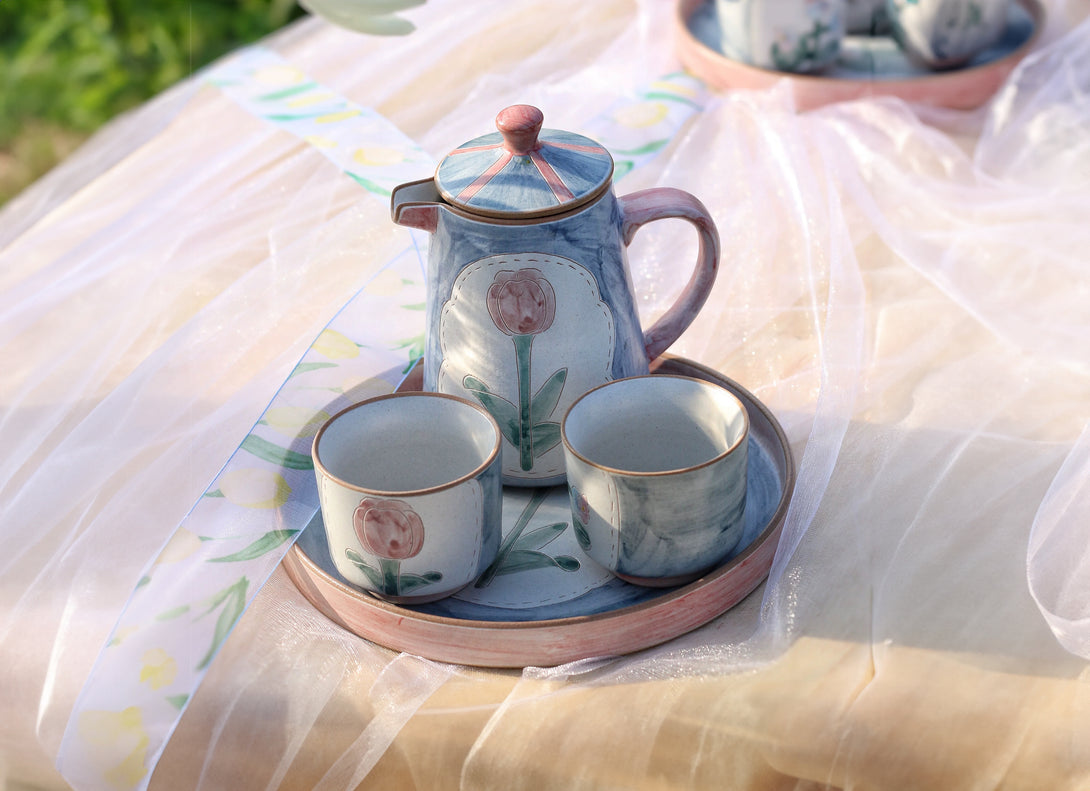 a set of teapot, cup and saucer in floral patterns, primarily in blue and pink colors.