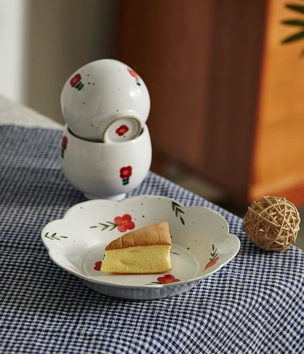 A white ceramic cup with red and green floral patterns on the side, displayed on a table.