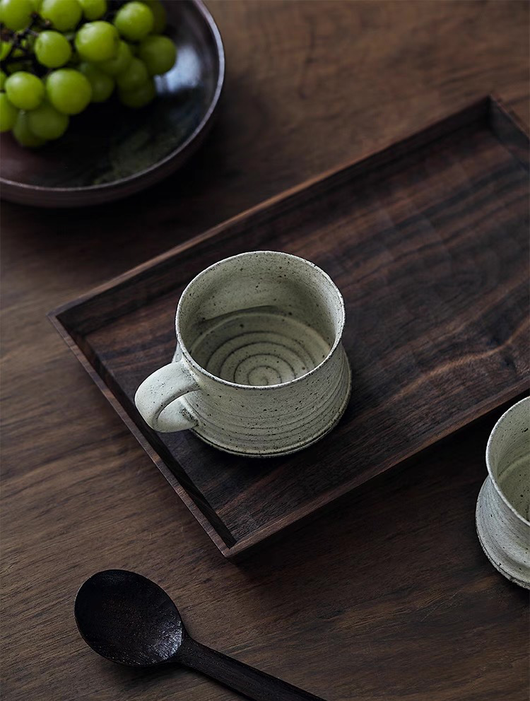 White ceramic cup on a wooden tray with grapes in the background