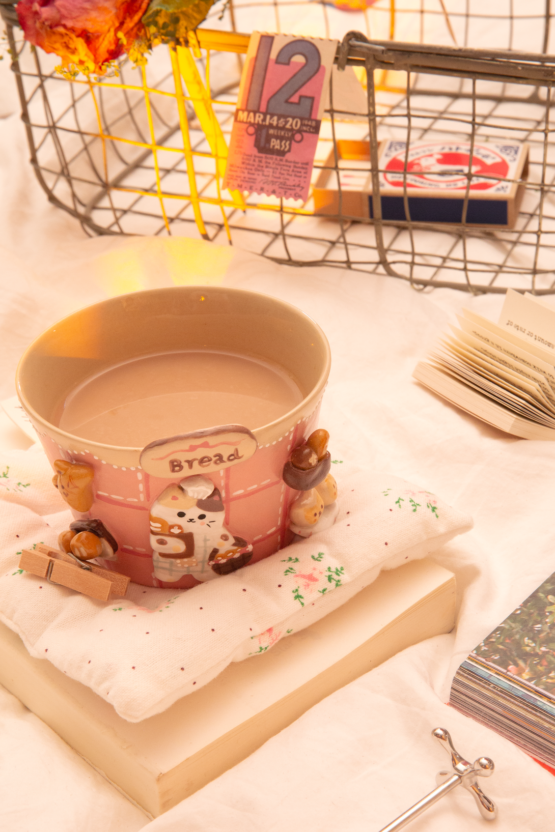 Ceramic mug with cartoon design on a soft surface with books and decorative items.