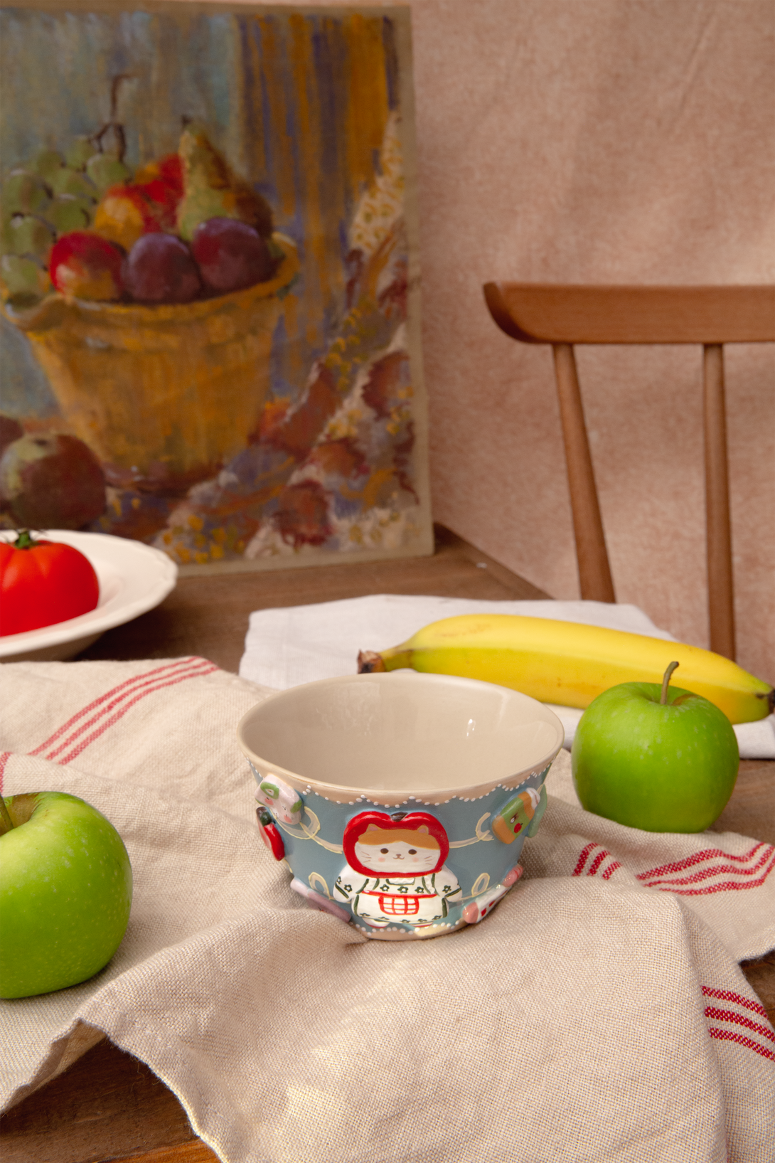 Ceramic bowl with a colorful design on a table with fruits and a painting in the background