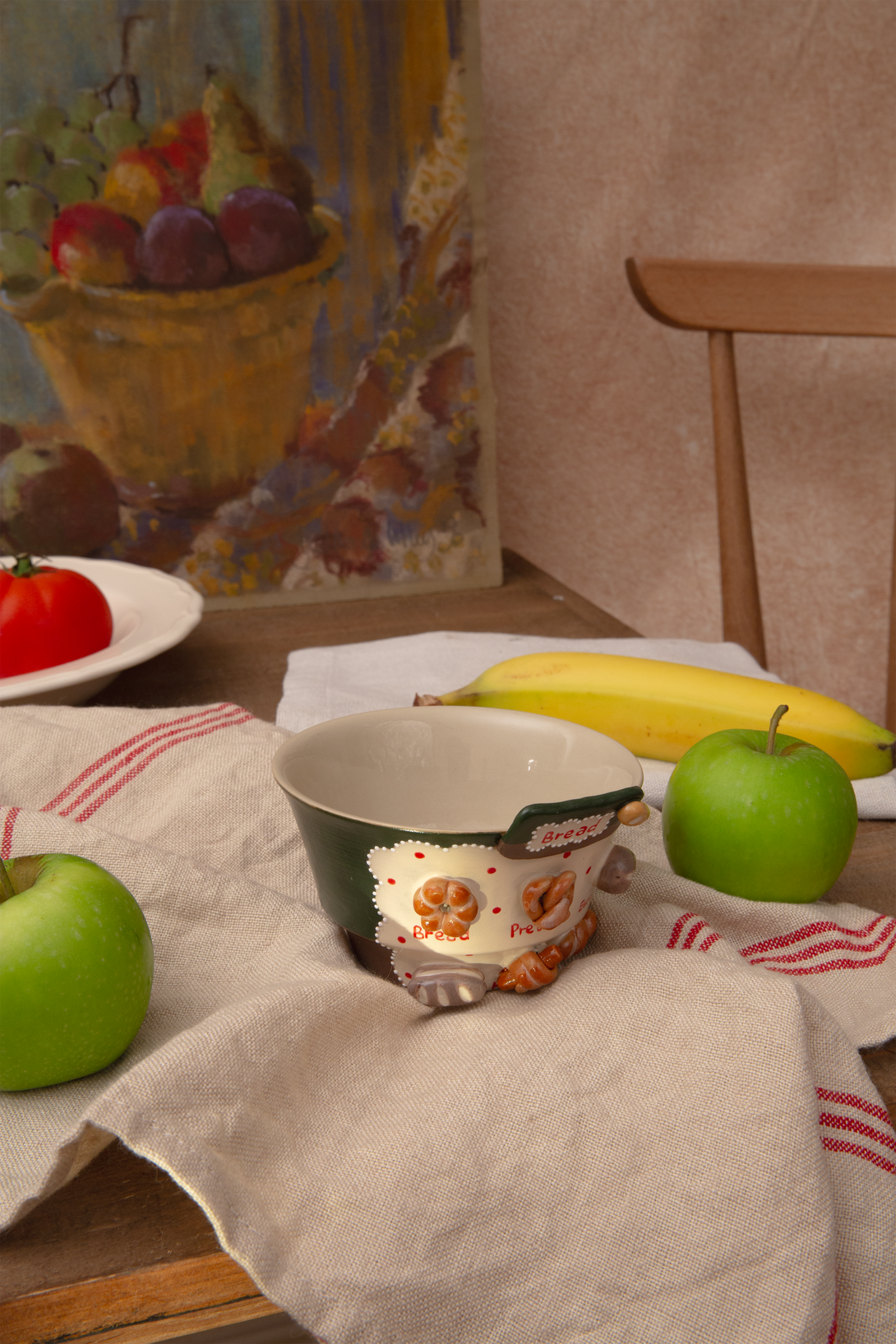 Fruit and a bowl on a table with a painting in the background
