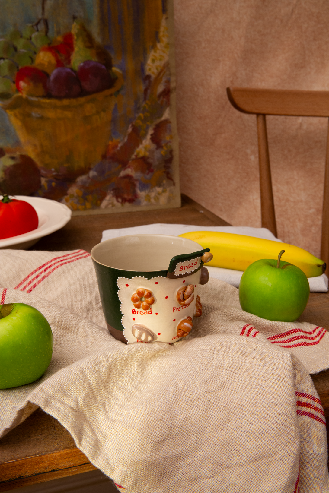 Table setting with a mug, apples, and bananas on a tablecloth.
