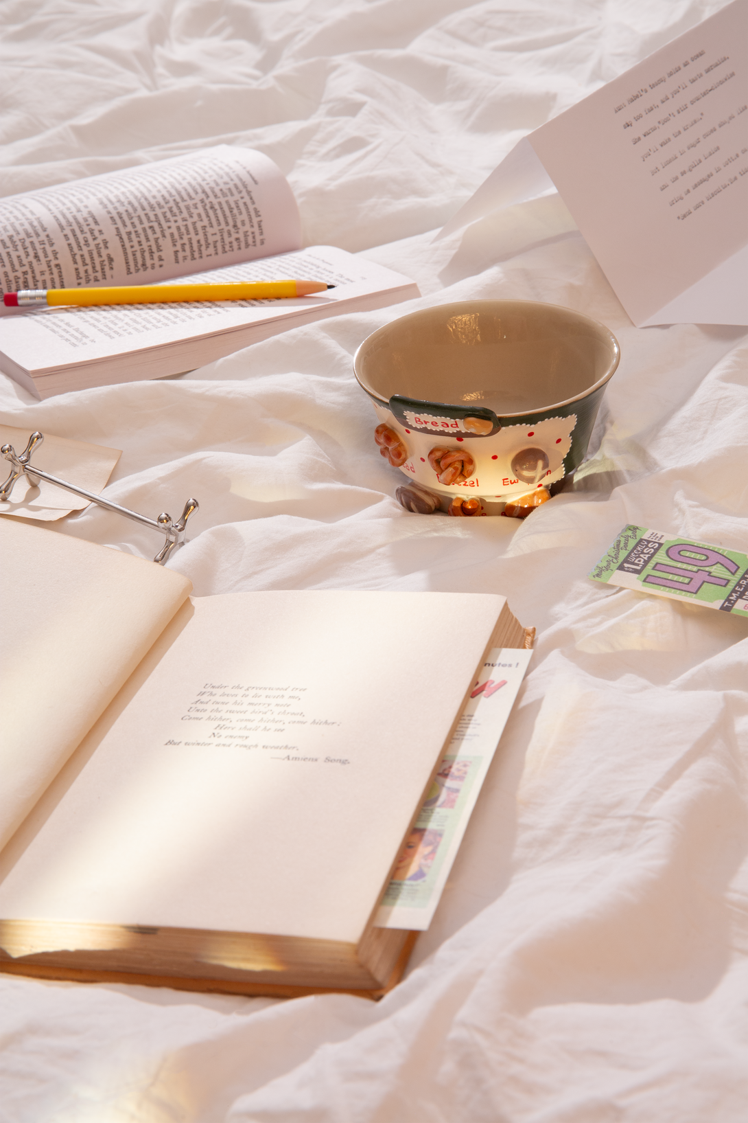 Open book, pencil, and bread-patterned cup on a white textured surface