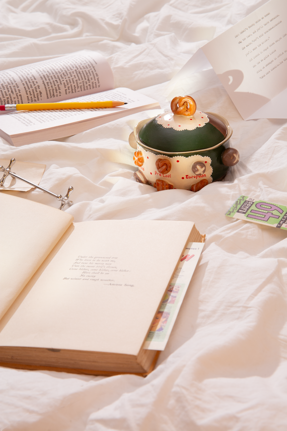 Open book, ceramic bowl, and pencil on a white textured surface