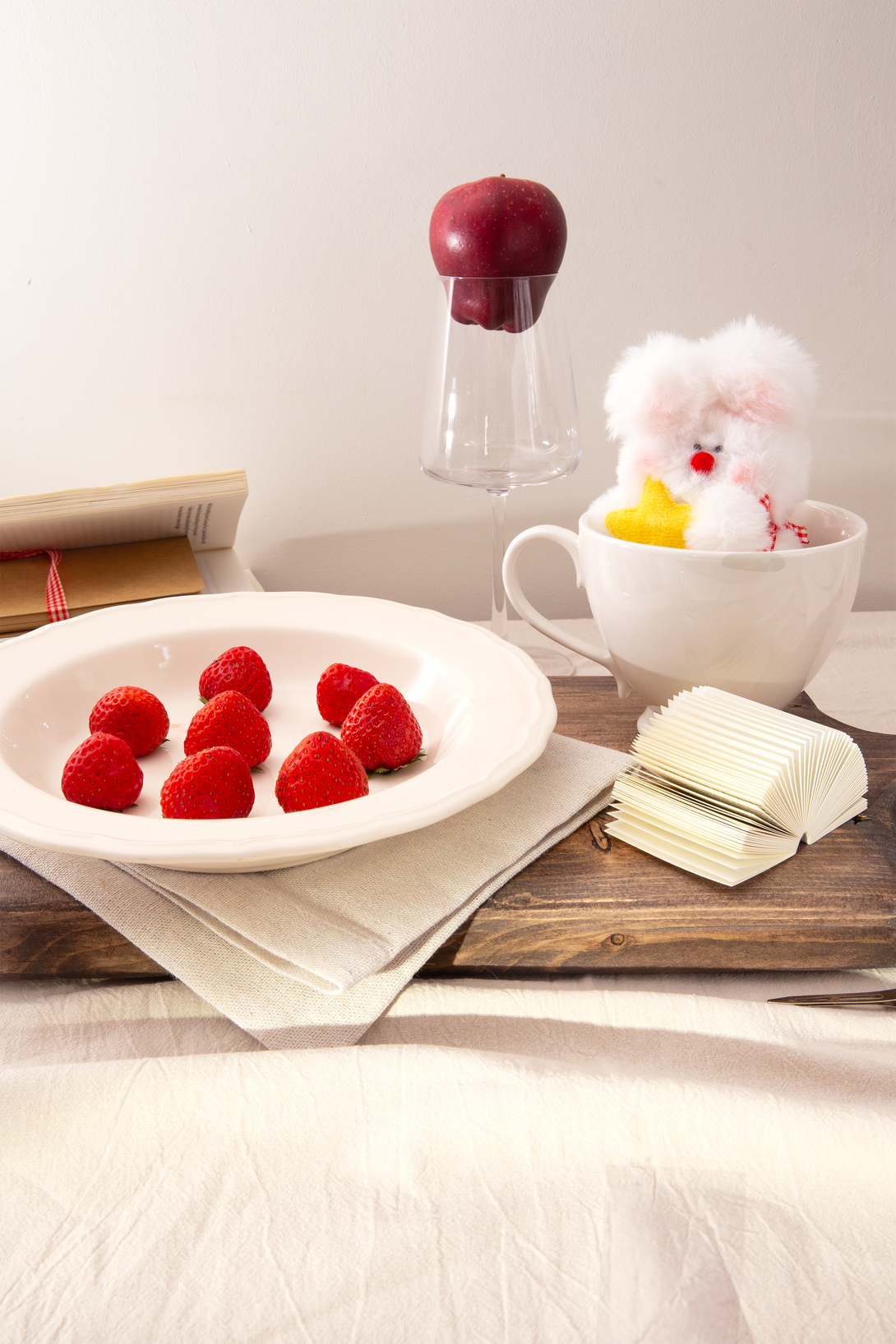 Plate of raspberries on a wooden table with a cup, a rabbit plush and other items.