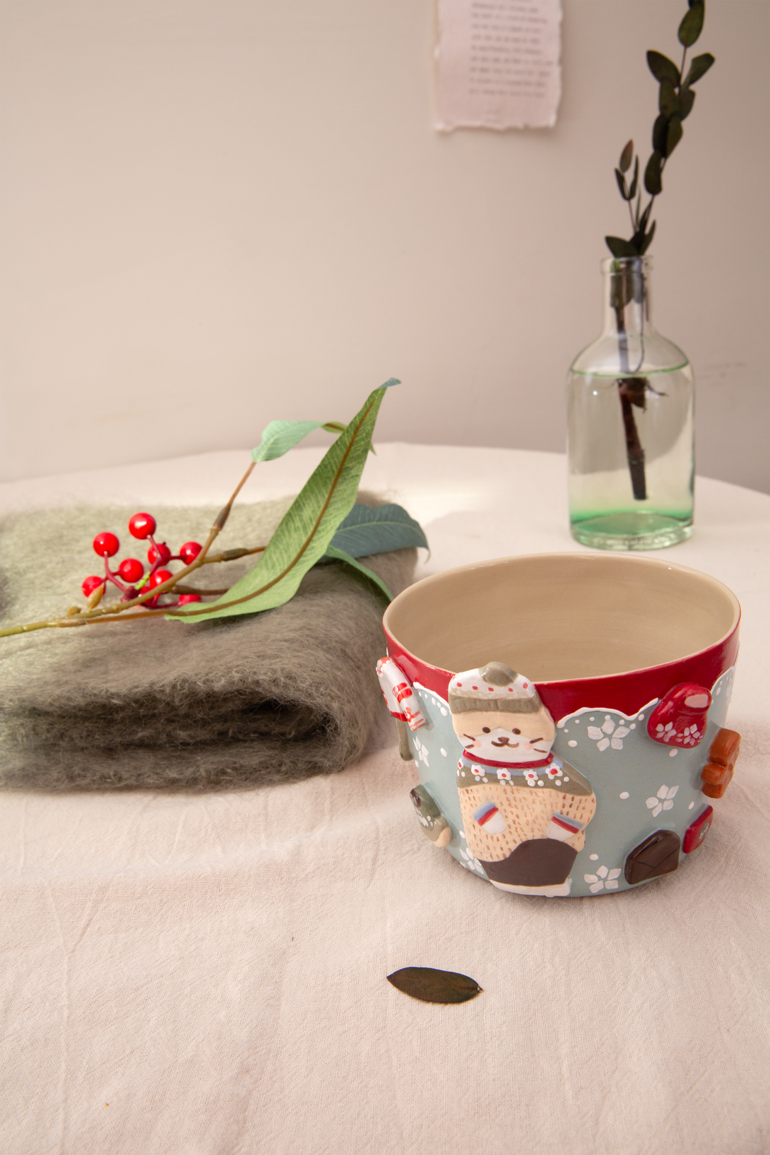 Handmade mug with cartoon characters on a table with a vase and plant in the background