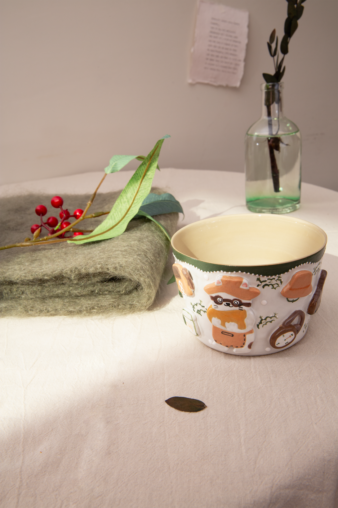 Ceramic cup with animal design on a white surface with a towel and decorative items.