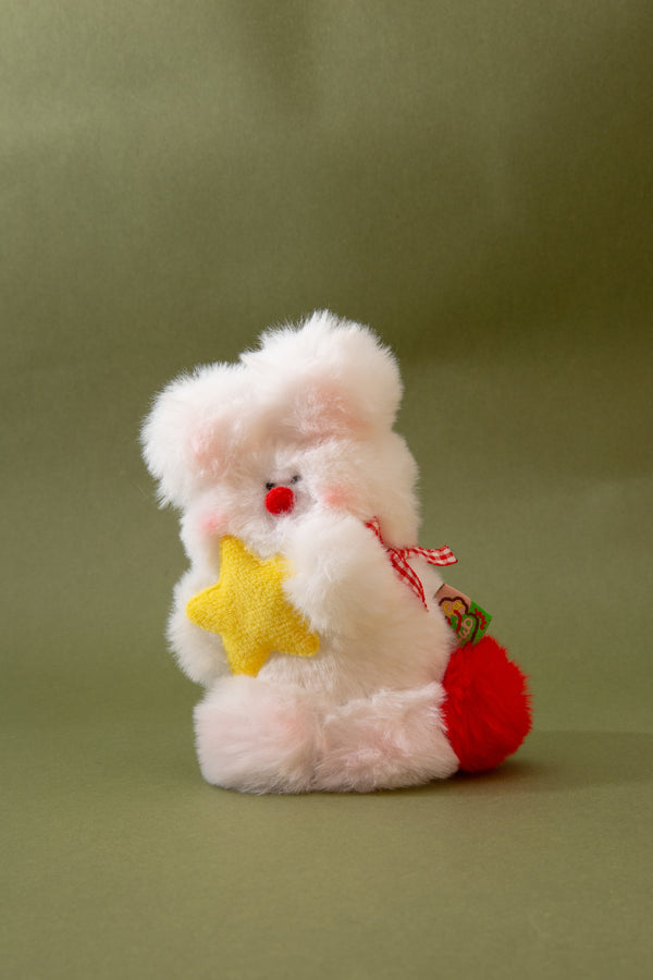 Plush key chain resembling a rabbit holding a yellow star and red bag on a green background
