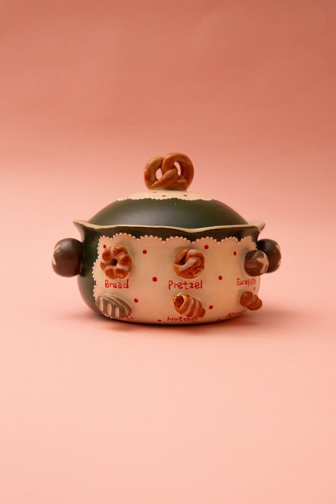 Ceramic lidded bowl with pretzel design on a pink background