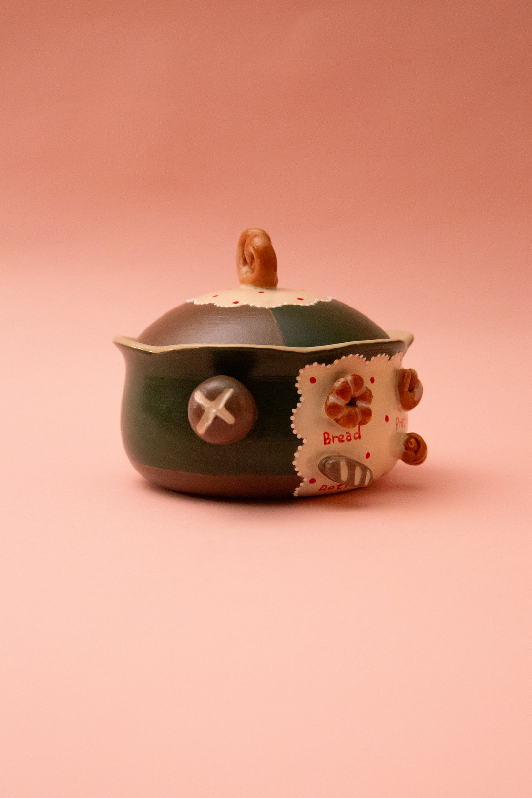 Ceramic bowl with lid and with decorative elements on a pink background