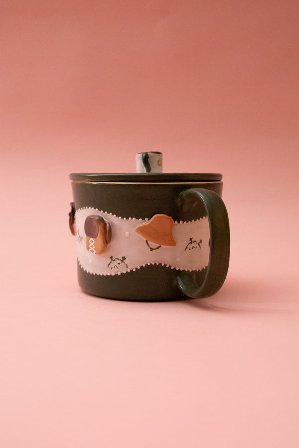 Ceramic mug with cartoon face design on a pink background