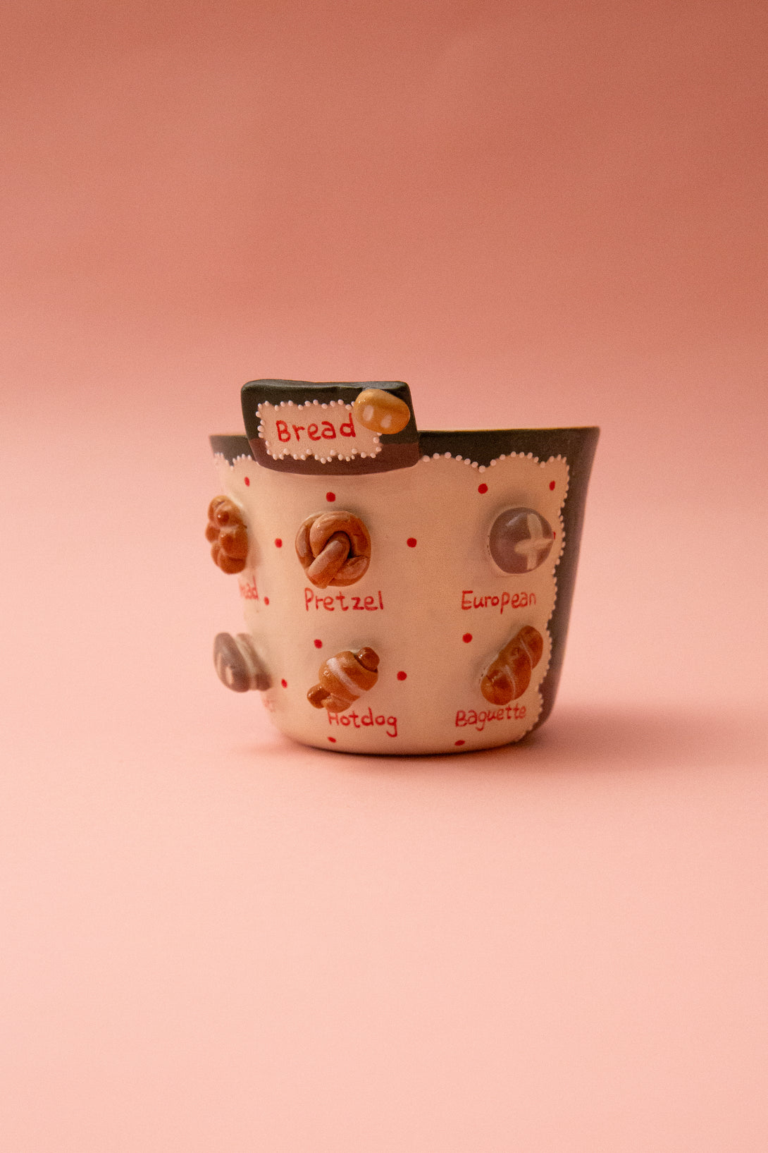 Ceramic mug with various food item illustrations on a pink background