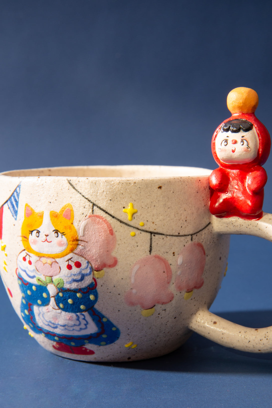 Ceramic mug with cartoon designs and a small figurine on a blue background