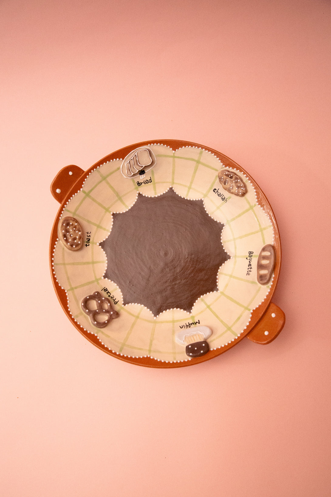 Round plate with handles on a pink background