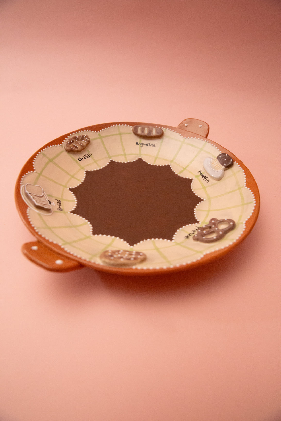 ceramic plate with bread themed illustrations on a pink background