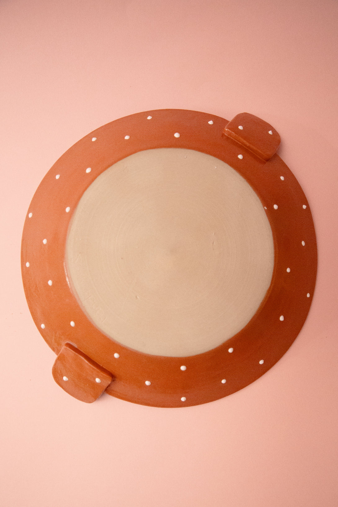 ceramic plate bottom view with white polka dots on a pink background