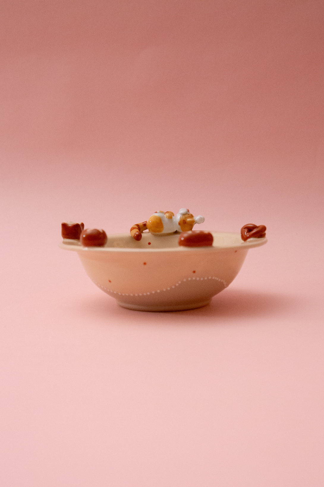 Small ceramic bowl with decorative elements on a pink background