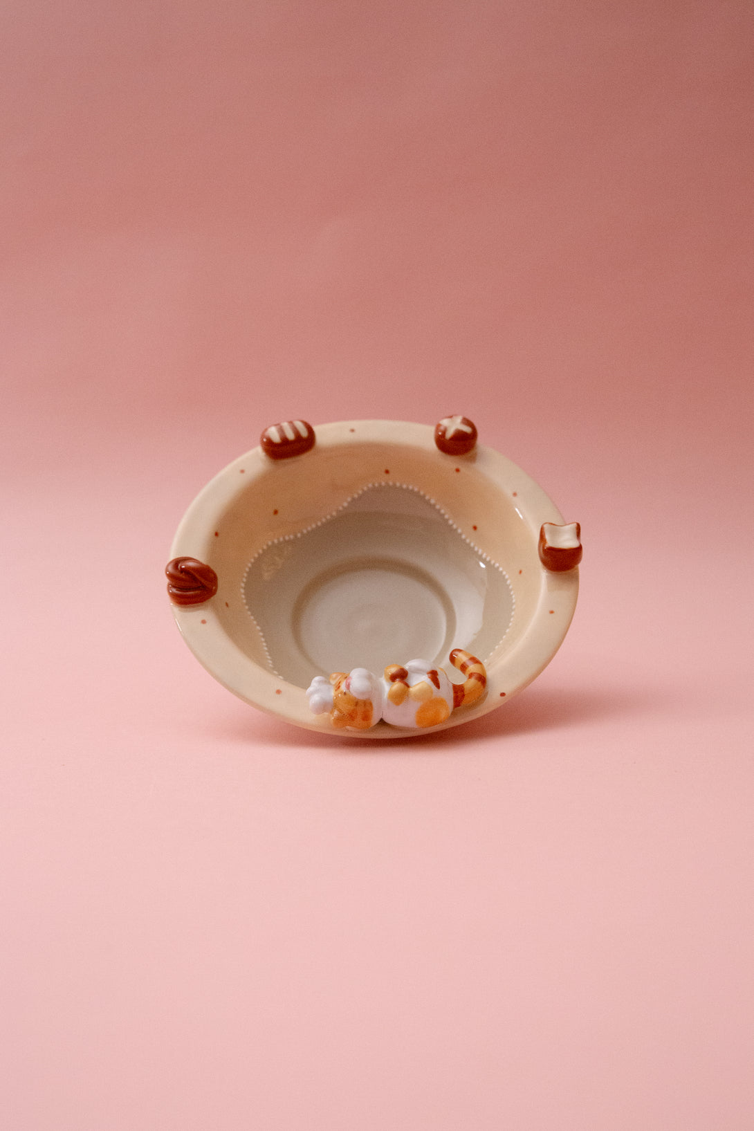 Ceramic bowl with cat paw handles on a pink background