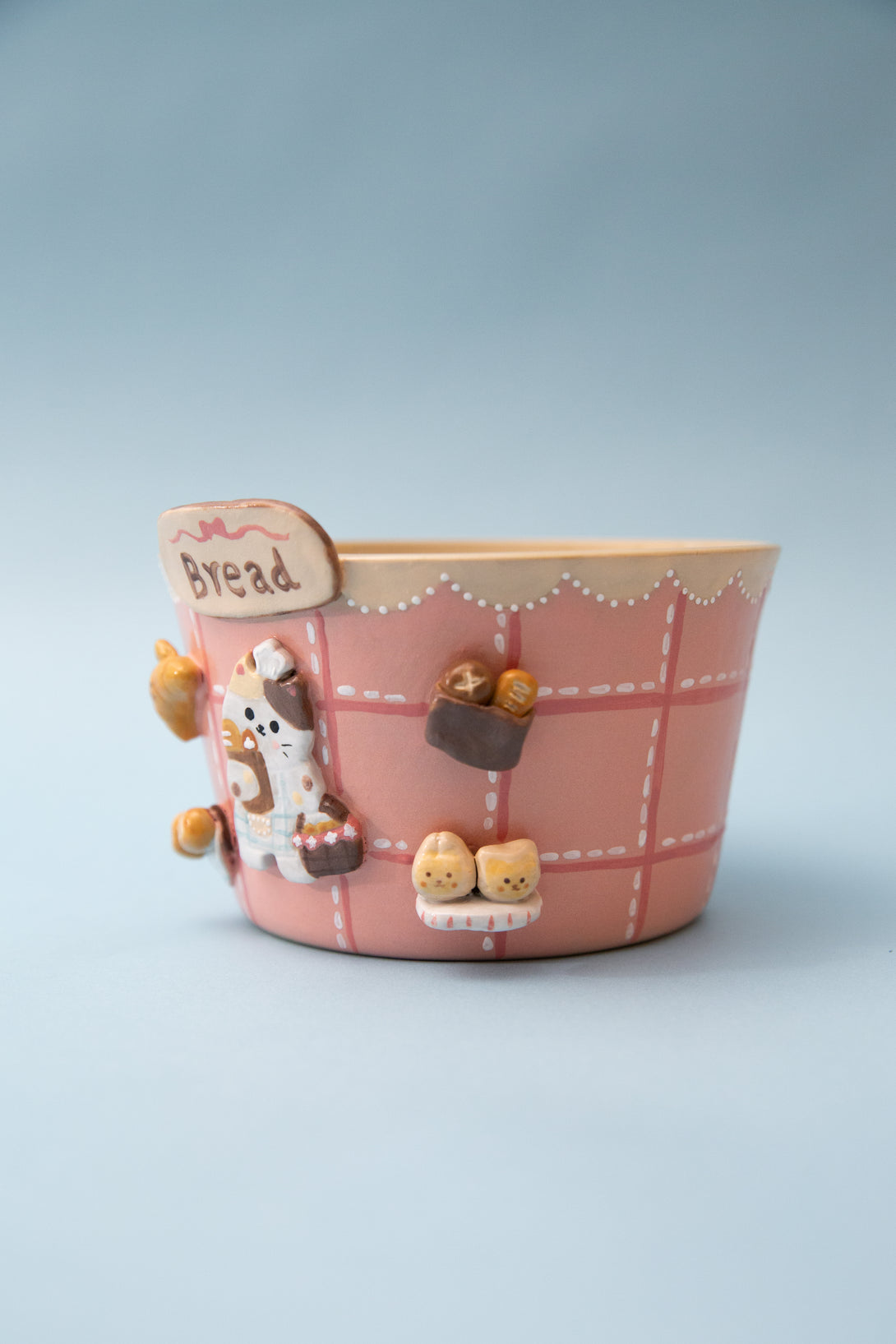 pink ramen bowl with cartoon character and small figures on a light blue background