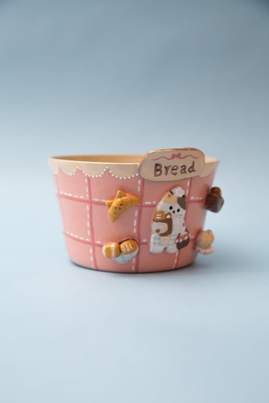 Pink ceramic ramen bowl with cartoon character and 'Bread' label on a light blue background