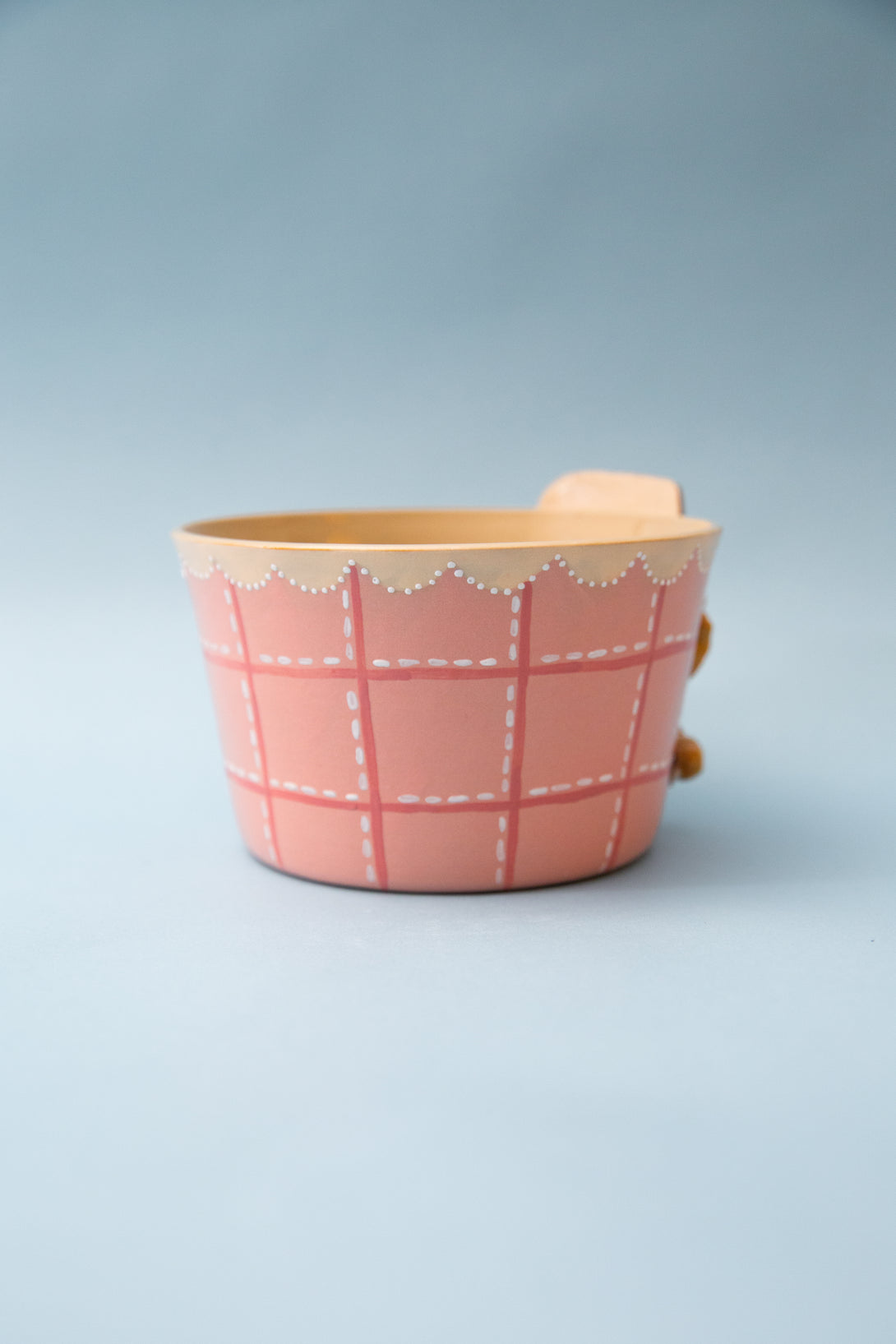 Pink ceramic salad bowl with plaid pattern on a light blue background