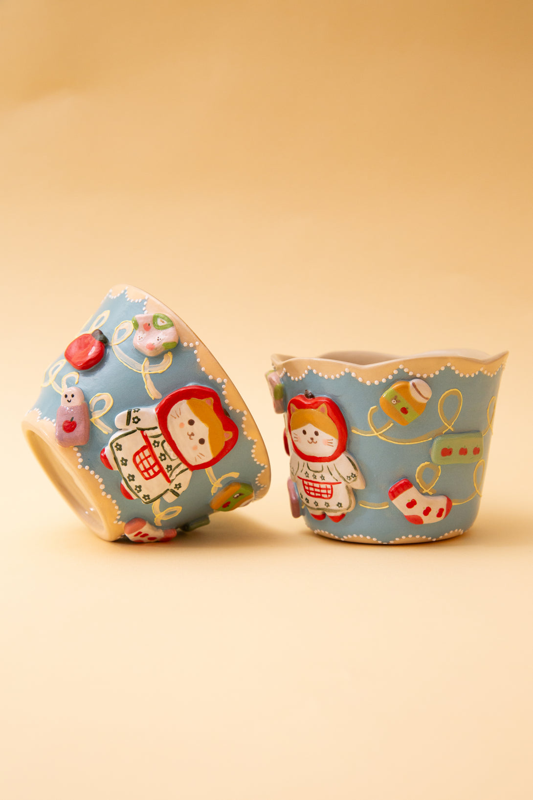 Two cups with cartoon character designs on a beige background
