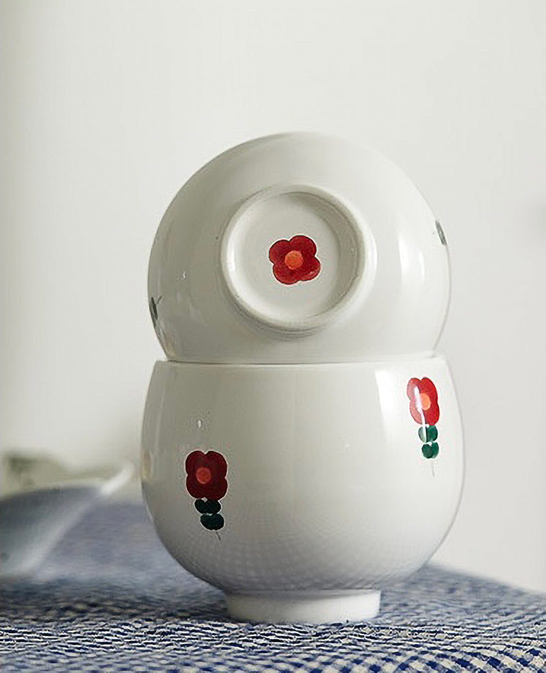 A white ceramic cup with red and green floral patterns on the side, displayed against a plain background.